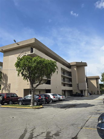 Front view of a multi-story apartment building with a parking area.