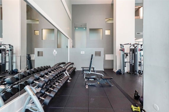 Indoor gym area with exercise equipment, including dumbbells and machines.