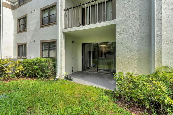 Front view of a multi-story building with balcony and sliding glass doors.