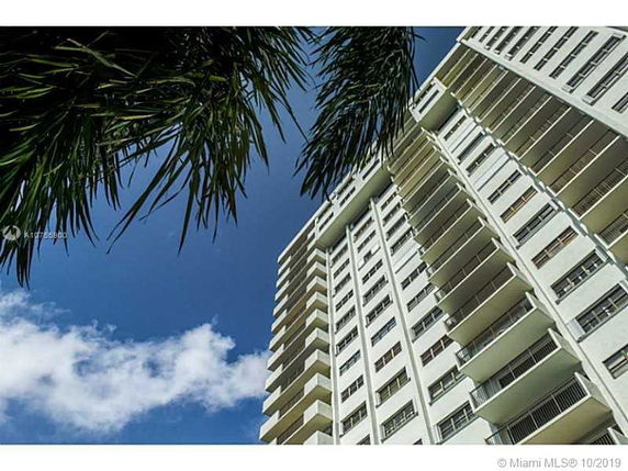 View looking up at a multi-story apartment building with balconies.