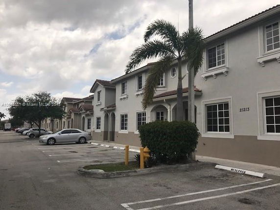 Front view of a two-story building with multiple units and a parking area.