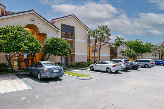 Front view of a multi-story apartment building with parking.