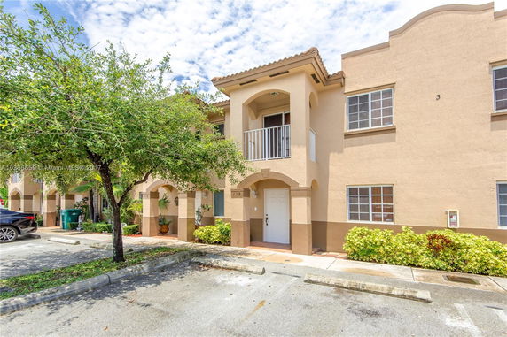 Front view of a two-story townhouse with arched entryways and a small balcony.