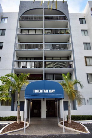 Front view of a multi-story building with balconies and an entrance canopy labeled 'TIGERTAIL BAY'.