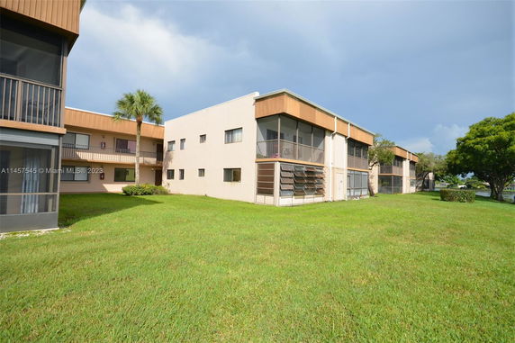 Rear view of a multi-story building with screened balconies and green lawn.