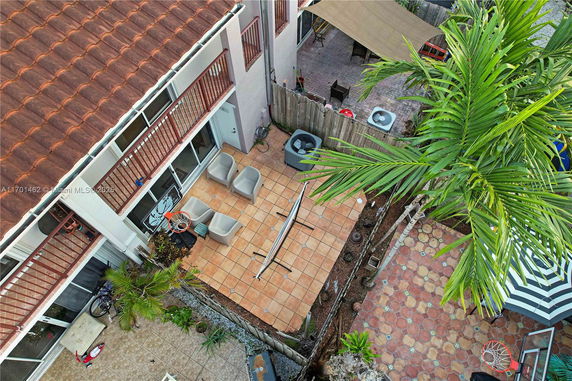 Aerial view of a roof with terracotta tiles overlooking a patio area with chairs and plants.