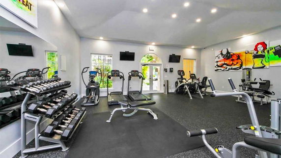 Interior view of a gym with various exercise equipment and colorful wall art.