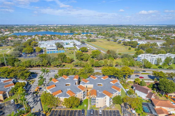 Panoramic view of residential and recreational buildings with surrounding landscape and distant lake.