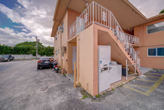 View of a two-story building with exterior stairs and parking area.