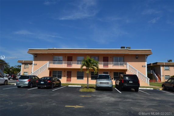 Front view of a two-story apartment building with parking area in front