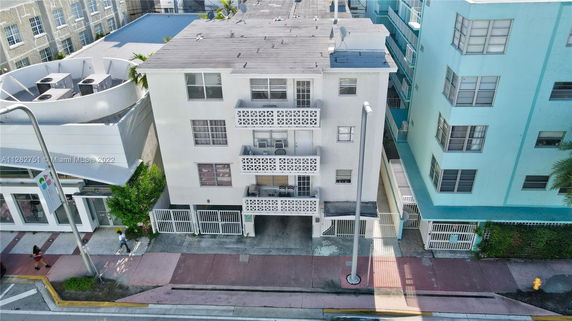 Front view of a multi-story building with balconies and gated parking.