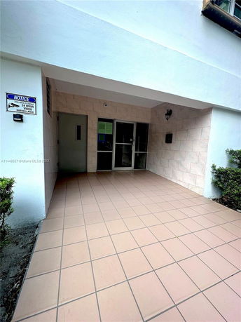 Entrance view of a building with tiled flooring and glass double doors.