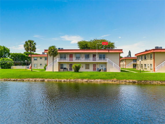 Front view of two-story apartment buildings with external staircases near a water body.