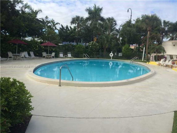View of outdoor swimming pool area with surrounding deck and chairs.