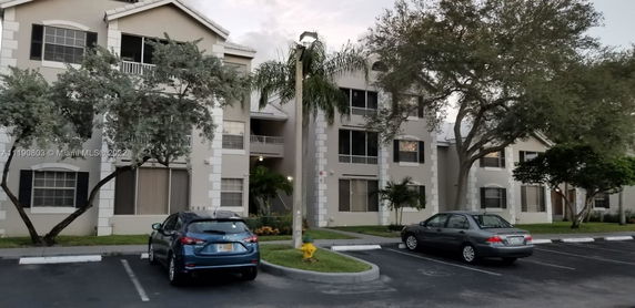 Front view of a multi-story apartment building with parking area.