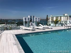 Rooftop swimming pool with lounge chairs and view of nearby buildings.