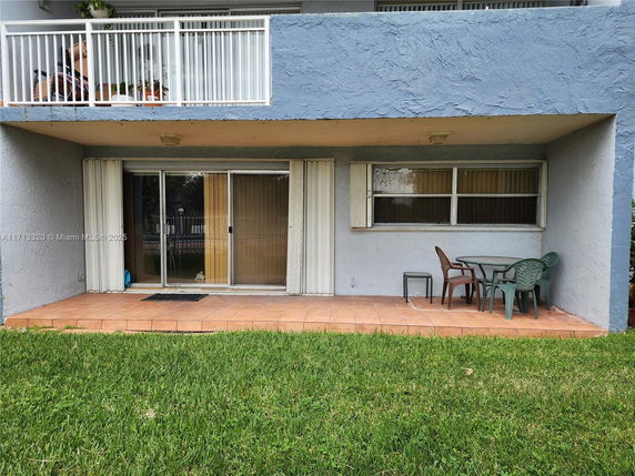 Front view of a ground-floor apartment with a sliding glass door and patio area.