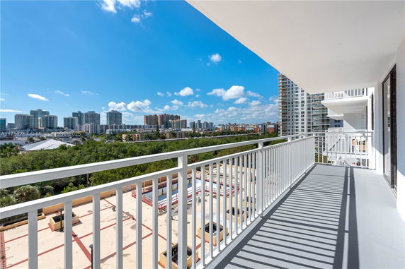 Panoramic view from a balcony overlooking city buildings and greenery.