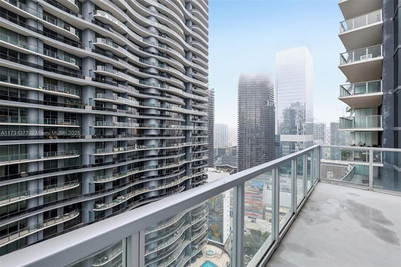 View of modern, high-rise buildings from a balcony with glass railings.