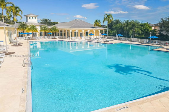 Large outdoor swimming pool with surrounding sun loungers and umbrellas.