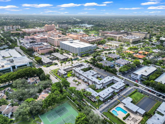 Aerial view of a suburban neighborhood with multiple buildings and a tennis court.