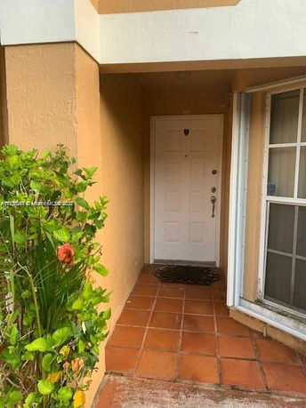 Front entryway of a house with a white door and terracotta tiles.
