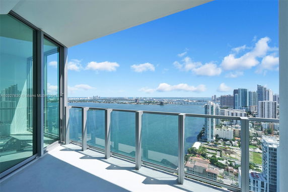 Panoramic view from a high-rise balcony overlooking a city skyline and water body.