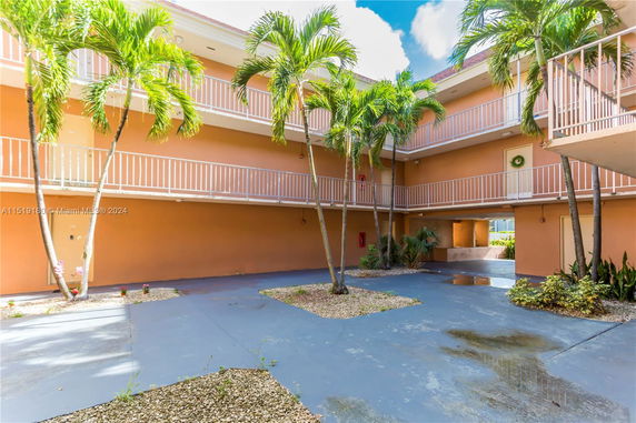 Courtyard view of a multi-story building with balconies and palm trees.