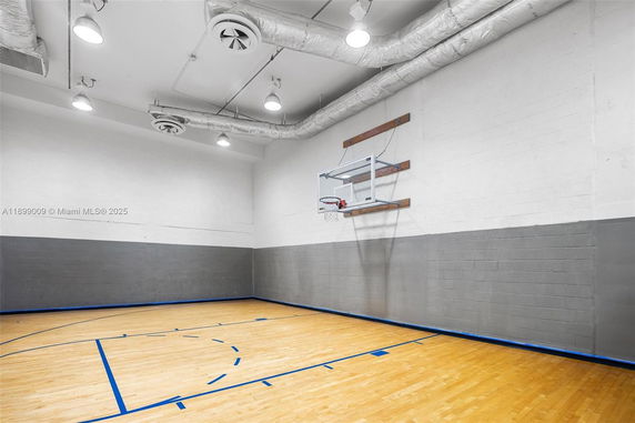 Indoor basketball court with wooden flooring and a basketball hoop on the wall.