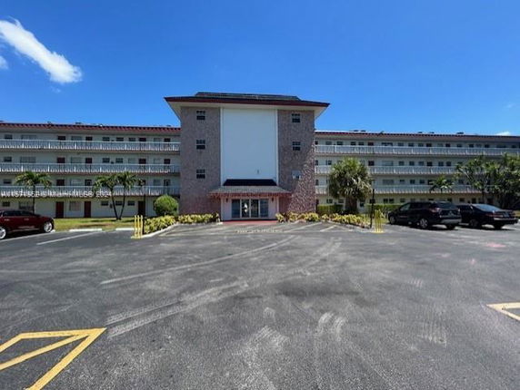 Front view of a multi-story residential building with parking area.