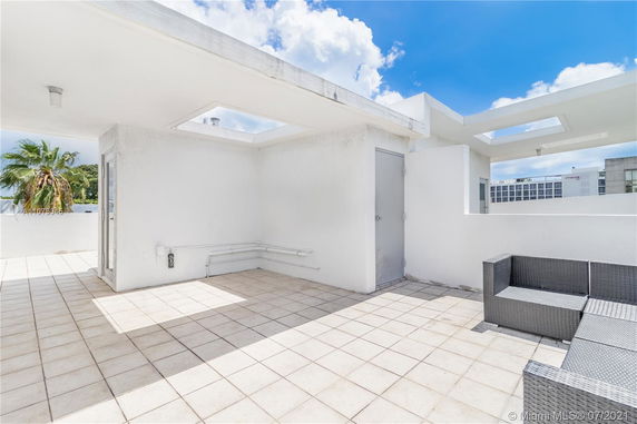 Open rooftop area with tiled flooring and a small seating arrangement.