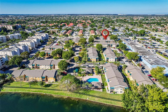 Aerial view of a residential neighborhood with multiple apartment buildings, parking areas, and a swimming pool, located near a water body.