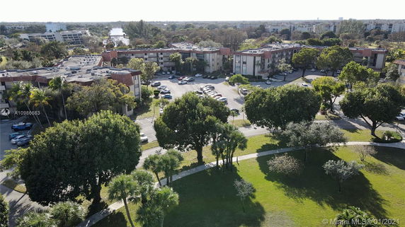 Aerial view of residential buildings surrounded by trees and parking areas.