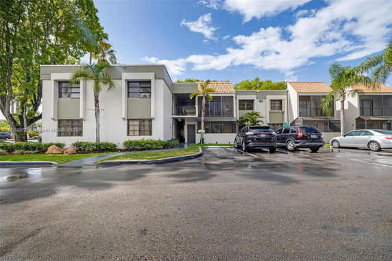 Front view of a two-story residential building with a parking area in front.