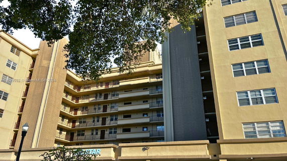 Front view of a multi-story residential building with balconies and multiple windows.