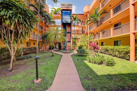 Front view of a multi-story residential building with balconies and lush landscaping.