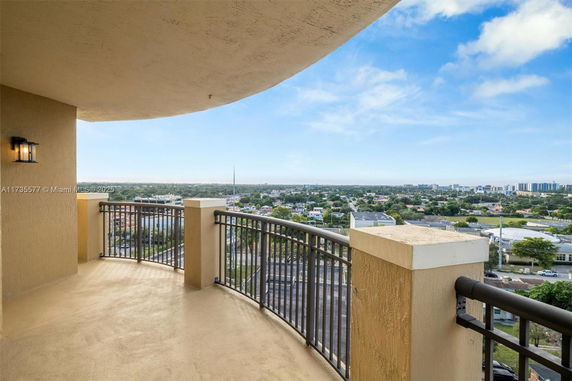 Panoramic view from a balcony overlooking cityscape with buildings and greenery.