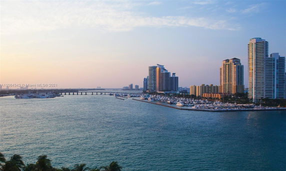 Panoramic view of a bay area with tall buildings, marina, and a bridge in the distance.