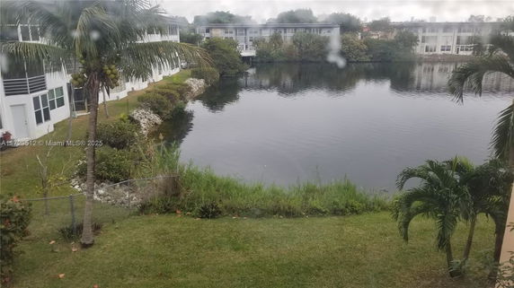 View of a small lake with buildings in the background.