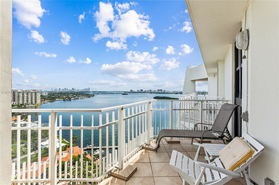 Balcony with a view of a body of water and distant cityscape.