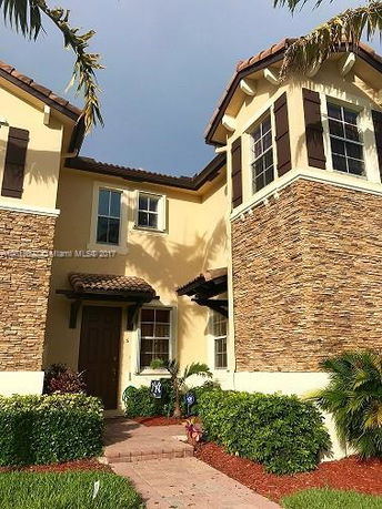 Front view of a two-story house with a stone facade and tile roof.