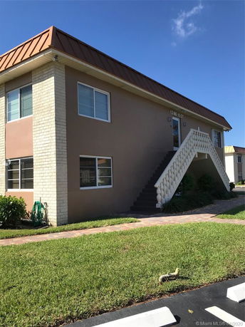Front view of a two-story building with exterior staircase and beige walls.