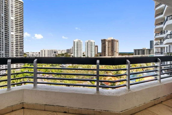 View from a balcony overlooking high-rise buildings and a pool area.