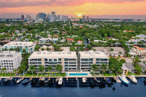 Aerial view of a cityscape featuring waterfront buildings and a skyline in the distance.