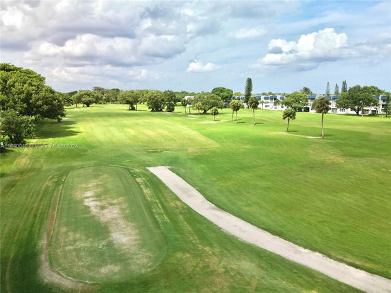 Panoramic view of a large green landscape with scattered trees and distant buildings.