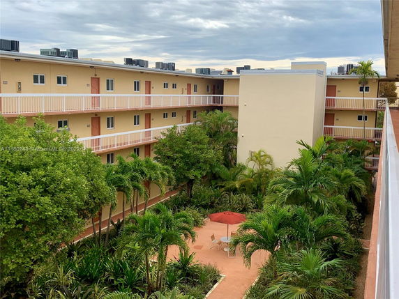 View of a multi-story residential building with balconies and a courtyard area with greenery.