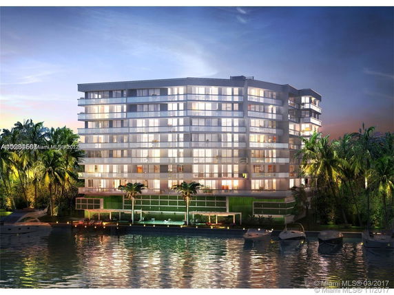 Front view of a multi-story modern apartment building with large glass windows and balconies, situated by the water.
