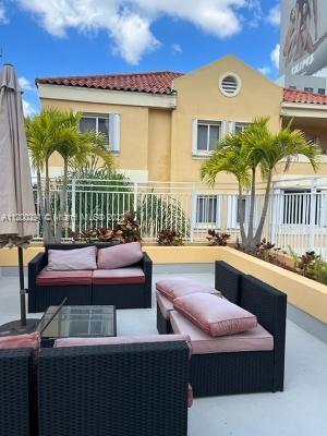Rooftop seating area with outdoor furniture and view of a two-story building.