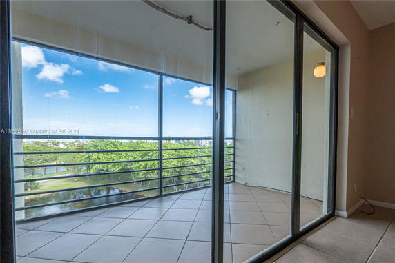 Balcony with glass railing overlooking a scenic view of trees and water.