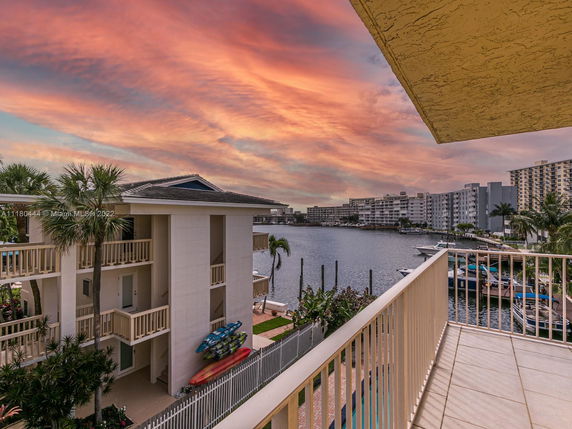 Panoramic view from a balcony overlooking a waterway with nearby residential buildings at sunset.